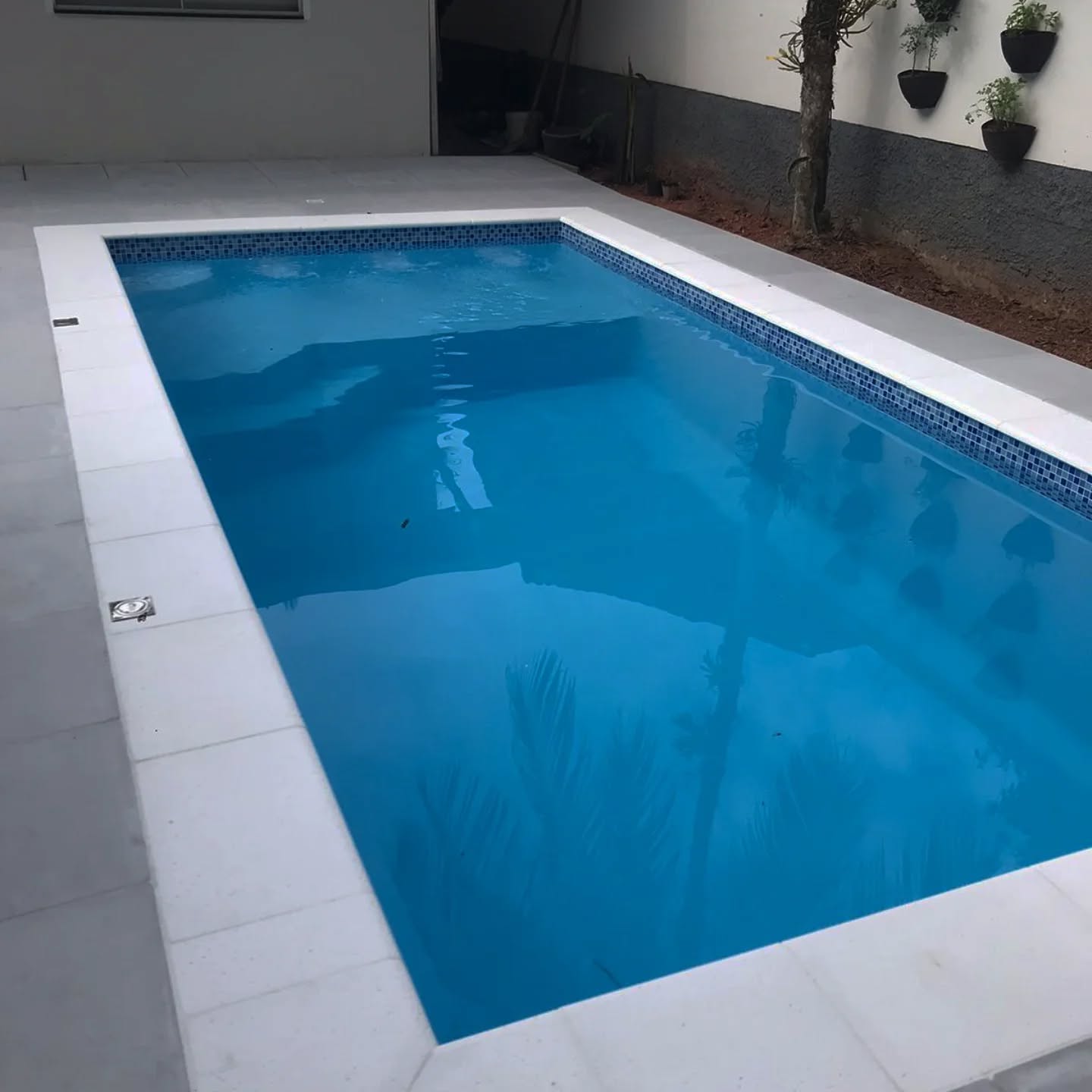 Piscina retangular azul com pastilhas em área residencial