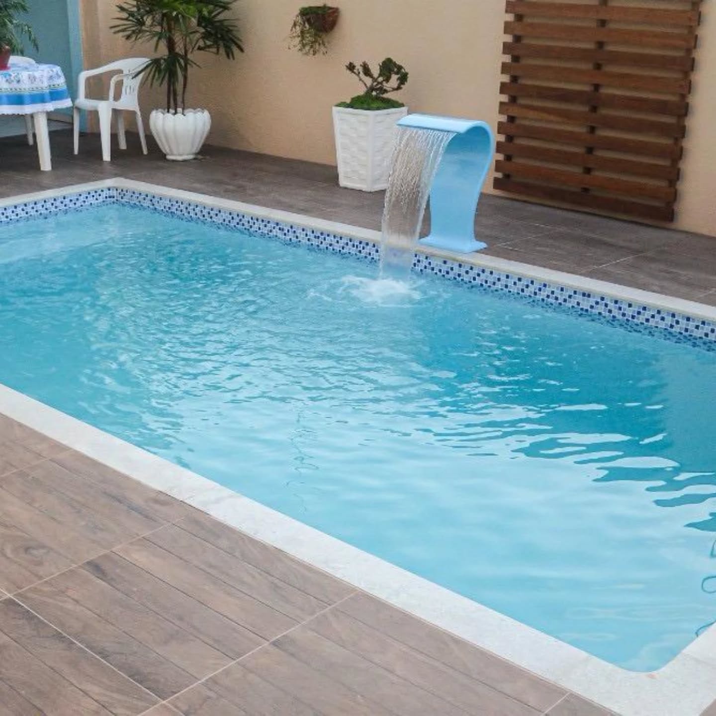 Piscina de fibra com cascata em área gourmet coberta