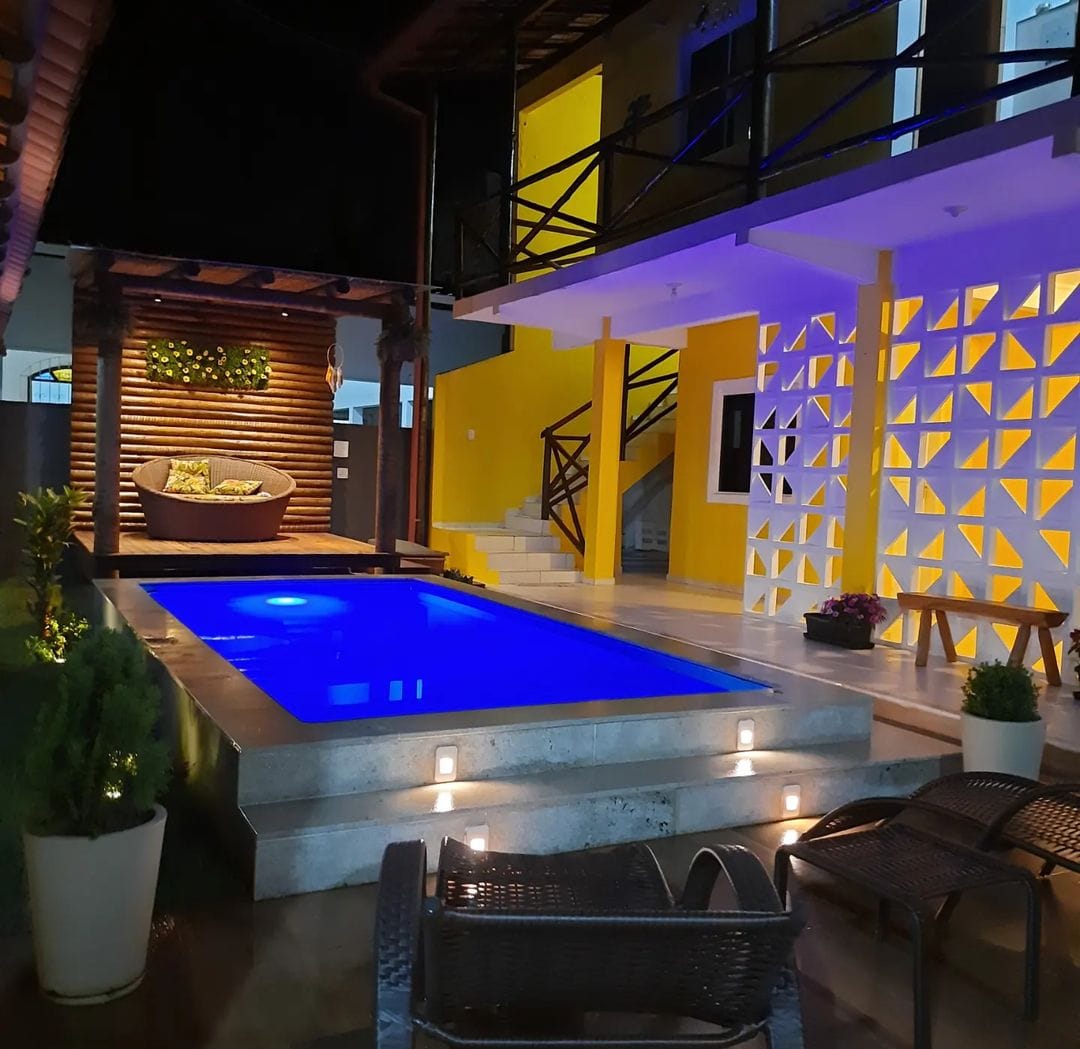 Piscina com iluminação LED azul à noite e área de lazer